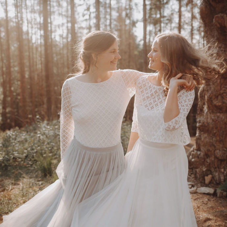 noni Brautkleider, lesbisches Brautpaar mit zweiteiligen Brautkleidern Spitzentops und Tüllröcken