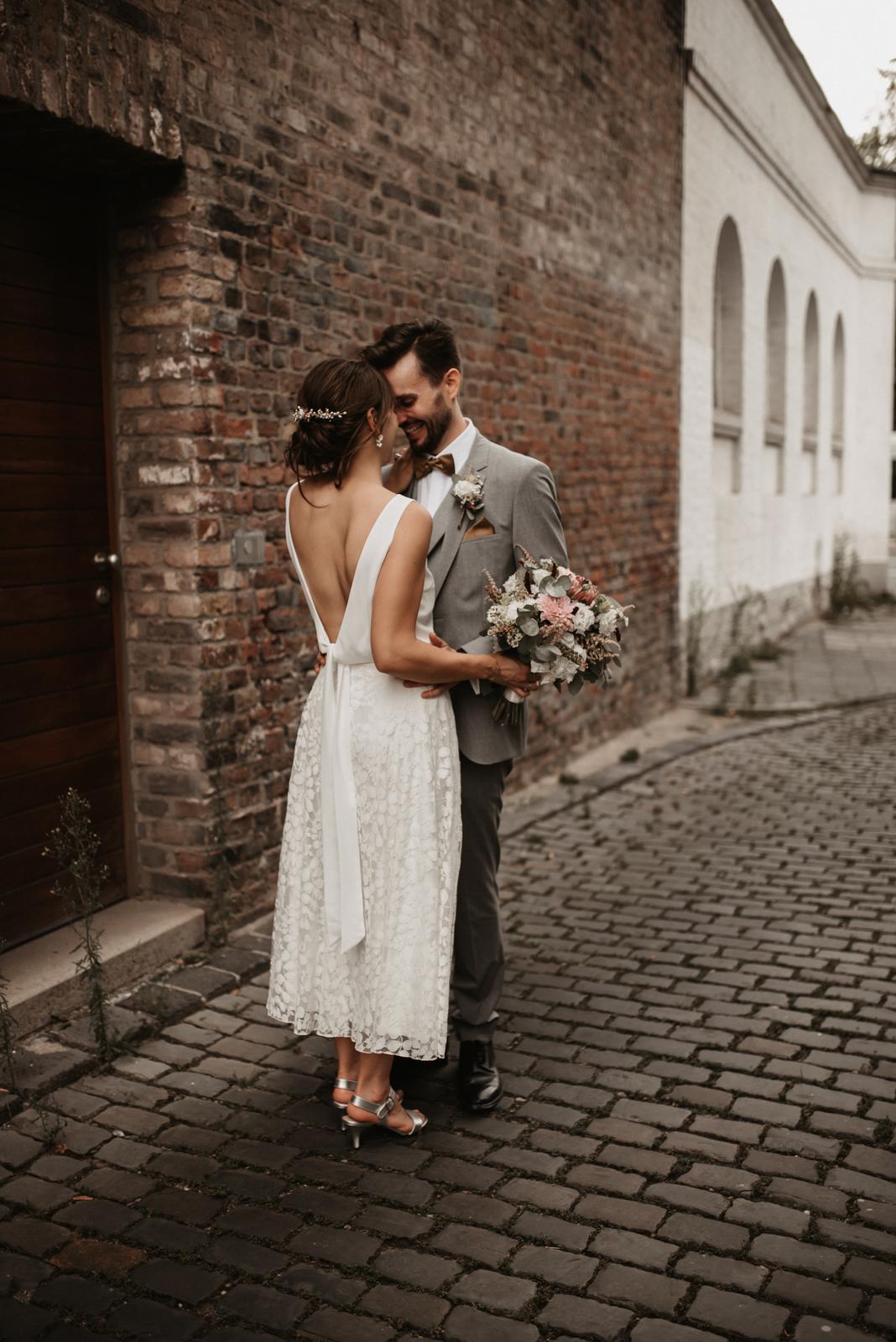 Brautpaar lachend, rückenfreies Brautkleid, Brautstrauss aus Trockenblumen mit Eukalyptus
