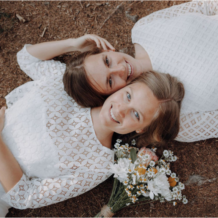 Zwei Frauen liegen auf einer Blumenwiese